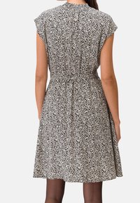 Korte mouwen, zwart-wit bloemenprint jurk met een uitlopende rok en geplooide details bij de achterkant van de hals. Zachte stofstructuur.