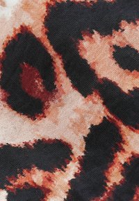 Tissu à imprimé léopard avec des nuances de noir, de marron et de crème, présentant une surface texturée et des éléments de motif abstraits tout au long.