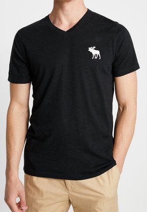 Czarna bawełniana koszulka z dekoltem w serek o dopasowanym kroju. Na lewej piersi mały biały nadruk z łosiem. Miła w dotyku.