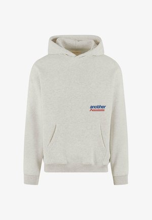 Gaiši pelēks kapucis izgatavots no mīksta auduma. Iespējo priekšējo kangaru kabatu, ribotas aproces un apakšmalu, kā arī mazu logo dizainu uz krūtīm.