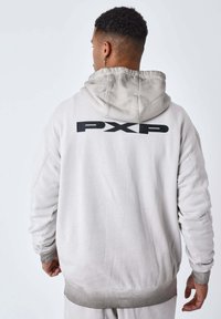 Felpa grigia chiara realizzata in materiale morbido, con un grande logo nero "PXP" sulla schiena, e polsini e orlo a costine per un look aderente.