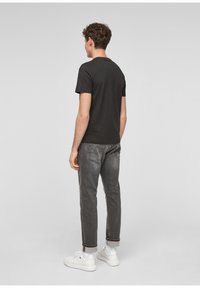 Zwarte korte mouwen T-shirt gecombineerd met grijze denim jeans en witte sneakers. Eenvoudig ontwerp dat zich richt op comfort en casual stijl.