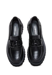 Schwarze Lederschuhe mit einer dicken Sohle, ausgestattet mit einer großen schwarzen Schnalle an der Vorderseite, glatter Textur und gesteppten Details entlang der Kanten.