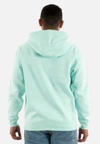 Sudadera verde menta con capucha ajustable, puños y dobladillo acanalados, fabricada con un tejido suave y texturizado. Diseño simple sin patrones destacados.