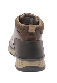 Hnedé ankle boots z imitácie kože s polstrovaným golierom, textúrovanými detailmi, kontrastným opätkom a protišmykovou podrážkou. Obsahujú pútko pre ľahké obúvanie.