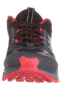 Černá a červená sportovní bota se syntetickým svrškem, texturovanými detaily, polstrovanou podrážkou a výrazným vzorem pro trakci na spodní straně.
