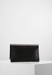 Bolso de mano negro de tela con forma rectangular plana y un ribete plateado adornado en la parte superior, con una textura suave.
