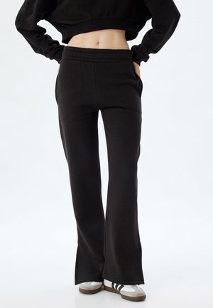 Zwarte sweatpants met een uitlopende pasvorm, voorzien van een elastische tailleband en zijzakken, gemaakt van zacht materiaal met een gladde textuur.