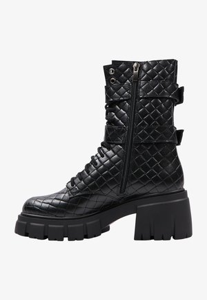 Bottines noires en cuir matelassé avec semelle plateforme épaisse, design à lacets sur le devant et fermeture éclair sur le côté ; présente des accents de boucle près du haut.