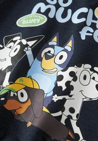 Fire tegneseriehunder i forskjellige farger og mønstre, inkludert en blå hund, en flekkete hund og en brun hund som har på seg en gul caps.