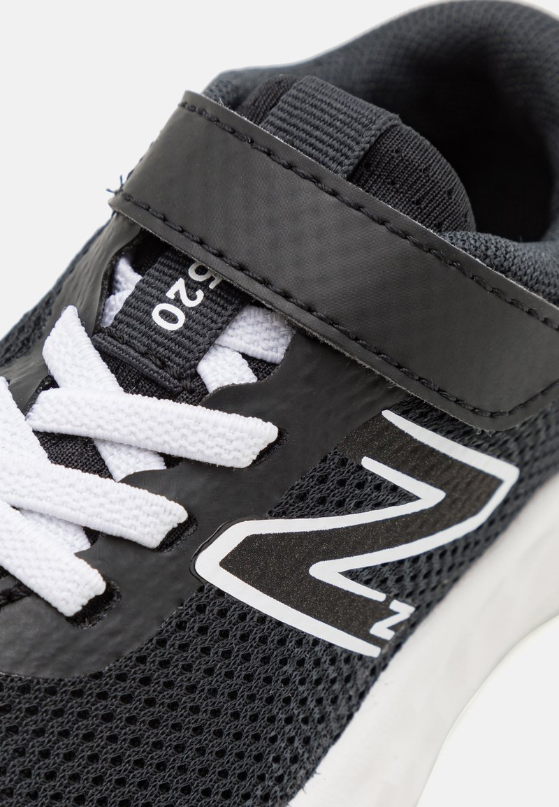 Scarpa sportiva nera con tomaia in rete, lacci bianchi e una fascia. Presenta un logo ben visibile e una suola in gomma testurizzata per una migliore aderenza.