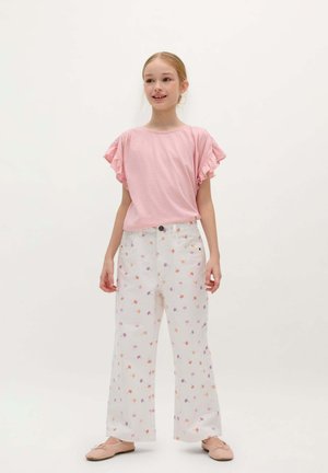 Light pink t-shirt with ruffled sleeves, paired with white wide-leg pants featuring a floral pattern in orange and purple. Simple ballet flats.