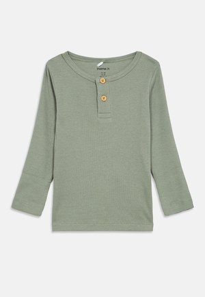 Langärmliges Henley-Shirt aus weichem, geripptem Stoff. Marmorierte grüne Farbe mit runder Ausschnitt, zwei Holzknöpfen und genähten Säumen.