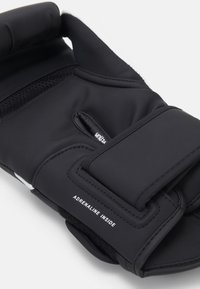 Black sports gloves made from soft textile, featuring a velcro strap and a textured grip surface. "Adrenaline Inside" printed on the palm.