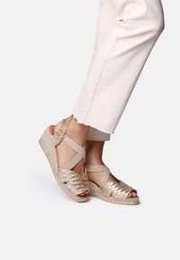 Woven metallic gold wedge sandals with crisscross straps, open toe design, and a textured jute platform sole.