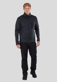 Black, lightweight, zip-up jacket with a high collar, featuring a chest pocket and side pockets; paired with black pants and boots.