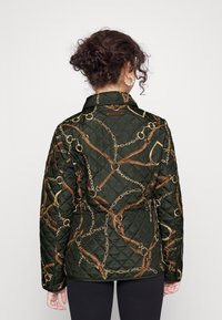 Kviltad jacka i mörkgrön med ett intrikat mönster av kedjor och läderremmar. Har krage och knapprad.