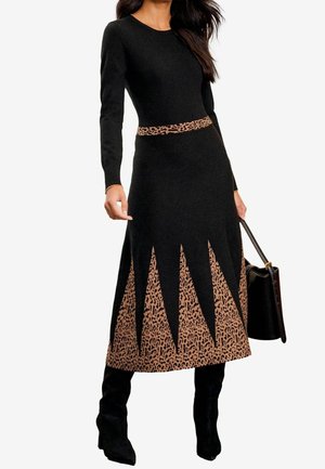 Robe noire à manches longues avec un haut ajusté et une jupe évasée. Comprend une ceinture à imprimé léopard et un motif géométrique à l'ourlet.