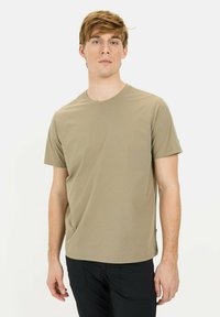 Kaki crew neck t-shirt lavet af blødt stof, med korte ærmer og lige kant. Bærer black pants, modellen står mod en hvid baggrund.