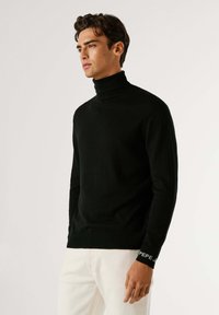 Maglione a collo alto nero realizzato in tessuto morbido. Presenta polsini a coste con il logo "PEPE". Design aderente con maniche lunghe e una texture liscia.