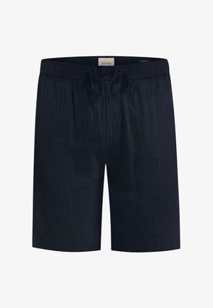 Sötétkék sort, texturált anyagból készült. Elastikus derékkal és húzózsinórral rendelkezik. Egyenes fazon, zsebek nélkül.