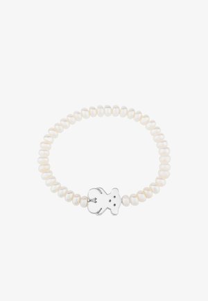 Pulsera de perlas con un diseño elástico, perlas blancas en forma ovalada y un charm de oso de plata en el centro.