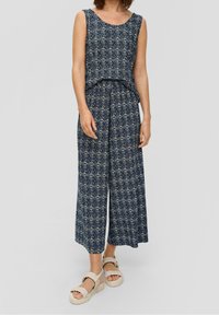 Combinaison bleu marine à motifs avec une coupe ample, manches courtes et pantalons larges. Le tissu présente des motifs complexes en beige et blanc.