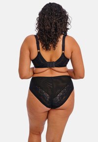 Conjunto de lencería negra que incluye un sujetador con tirantes ajustables y acentos de encaje, combinado con braguitas de cintura alta con paneles transparentes y detalles de encaje.