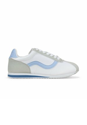 Zapatilla blanca con acentos en gris claro y azul. Parte superior de cuero suave, talón gris texturizado y un diseño lateral ondulado. Suela de goma con tracción.
