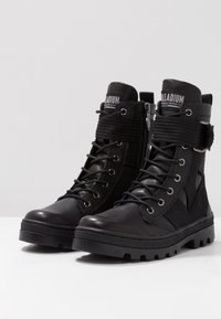 Stivali neri alla caviglia con una combinazione di pelle e tessuto testurizzato, dotati di design con lacci, zip laterale e suola robusta.
