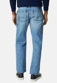 Pantalones cargo de mezclilla azul claro con amplios bolsillos traseros y un corte recto, presentando una textura desgastada y puños enrollados.