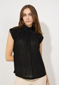 Kurzes schwarzes Top mit hohem Ausschnitt, gef alteter Vorderseite und Kap sleeves; leichtes Material mit etwas transparenter Textur.