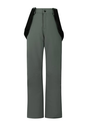 Jongen staat, draagt een grijze zip-up top, groene sneeuwbroek met zwarte bretels en zwarte laarzen tegen een effen lichte achtergrond.