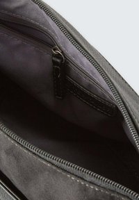 Schwarze Reisetasche mit einer glatten Außentextur, ausgestattet mit einem grauen Stoffinnenraum, sichtbarem Reißverschluss und subtilen Stichdetails.