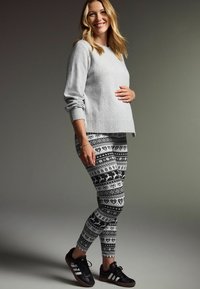 Grå strikket sweater og sorte leggings med hvide vintermønstre, der har hjerter og dyr, kombineret med sorte sneakers.