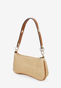 Bolso de paja trenzada con forma curva, acentos de piel en color marrón claro y una correa desmontable con herrajes dorados y detalles de broche.