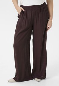 Loose, wide-leg pants in a deep burgundy fabric with a textured finish; features an elastic waistband and side pockets.