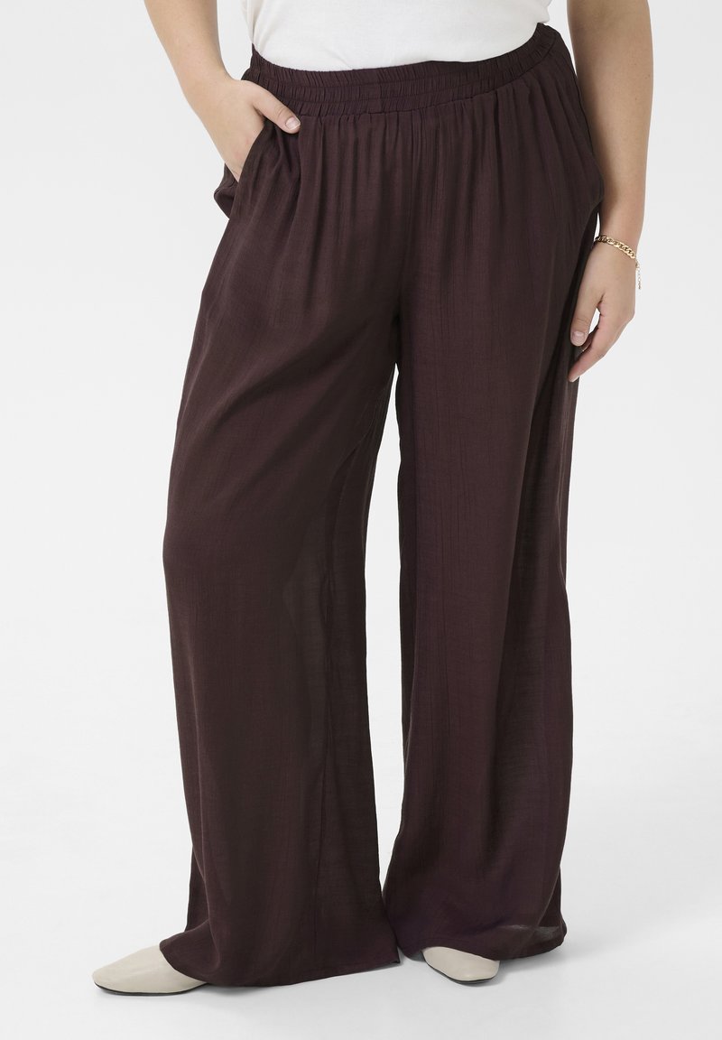 Loose, wide-leg pants in a deep burgundy fabric with a textured finish; features an elastic waistband and side pockets.