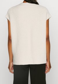 Hellbeige ärmelloses Strickoberteil mit rundem Ausschnitt, geripptem Saum und weicher Textur. Minimalistisches Design ohne sichtbare Muster oder Logos.