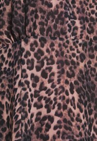 Tejido de estampado de leopardo que presenta una mezcla de manchas marrón oscuro y negro sobre un fondo rosa claro, con una textura acanalada y detalles fruncidos.