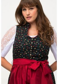 Bodice de dirndl traditionnel en noir avec motif floral, associé à une jupe en satin rouge et un ruban. Présente des manches en dentelle et des boutons en argent.