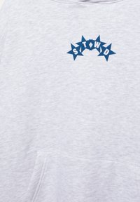 Világosszürke pulóver kék csillagformákkal, amelyek ívet képeznek, és fehér "STWID" betűkkel a felső mellrészen.