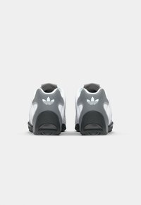 Adidași albi și gri, cu o talpă din cauciuc texturat, guler căptușit și detaliu cu logo pe călcâi.