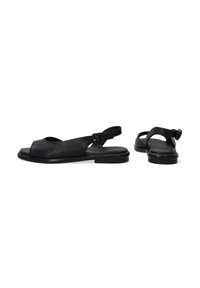 Schwarze Leder-Sandalen mit offenem Zehenbereich, Slingback-Riemen und flacher Sohle. Mit runder Aussparung und verstellbarem Schnallenverschluss für eine optimale Passform.