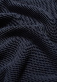 Marinblått texturerat tyg med ett ribbat mönster, vikt för att visa djup och mjukhet. Lämplig för olika textiltillämpningar.