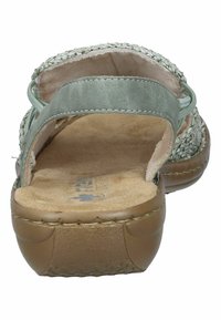 Öppen tå sandal med en vävd ovandel i ljusbeige, ett grönt satinband och en dämpad tan fotbädd med en texturerad sula.