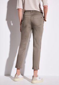 Pantalons khakis à coupe slim, avec cinq poches et taille mi-haute. Associés à des baskets blanches avec des accents beiges.