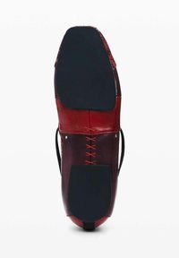 Rode leren schoen met een platte zool, voorzien van veters aan de zijkant en een contrasterende zwarte rubberen buitenzool. Glad oppervlak met een glanzende afwerking.