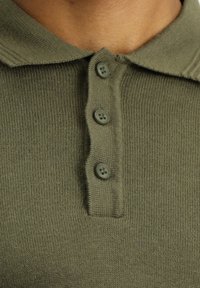 Koszulka polo z krótkim rękawem w kolorze oliwkowym, uszyta z tkanej dzianiny, z dwu guziczkowym zapięciem i klasycznym kołnierzykiem.