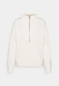 Pull en tricot blanc avec un col montant et une fermeture éclair quart. Présente une finition texturée et des épaules tombantes, offrant une coupe décontractée.